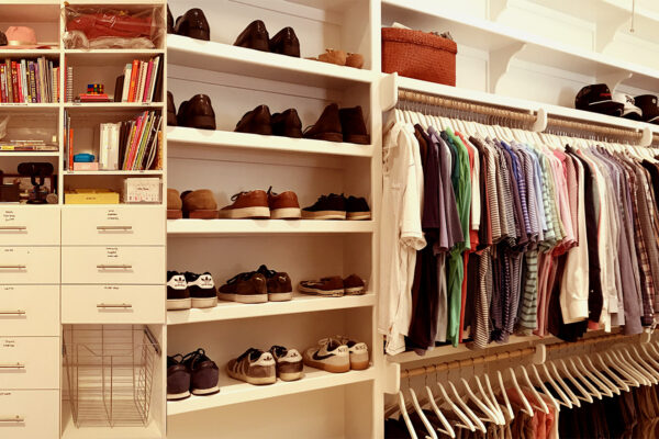 A well-organized closet, with shelves arranged, and shoes on shelves and clothing on hangers.